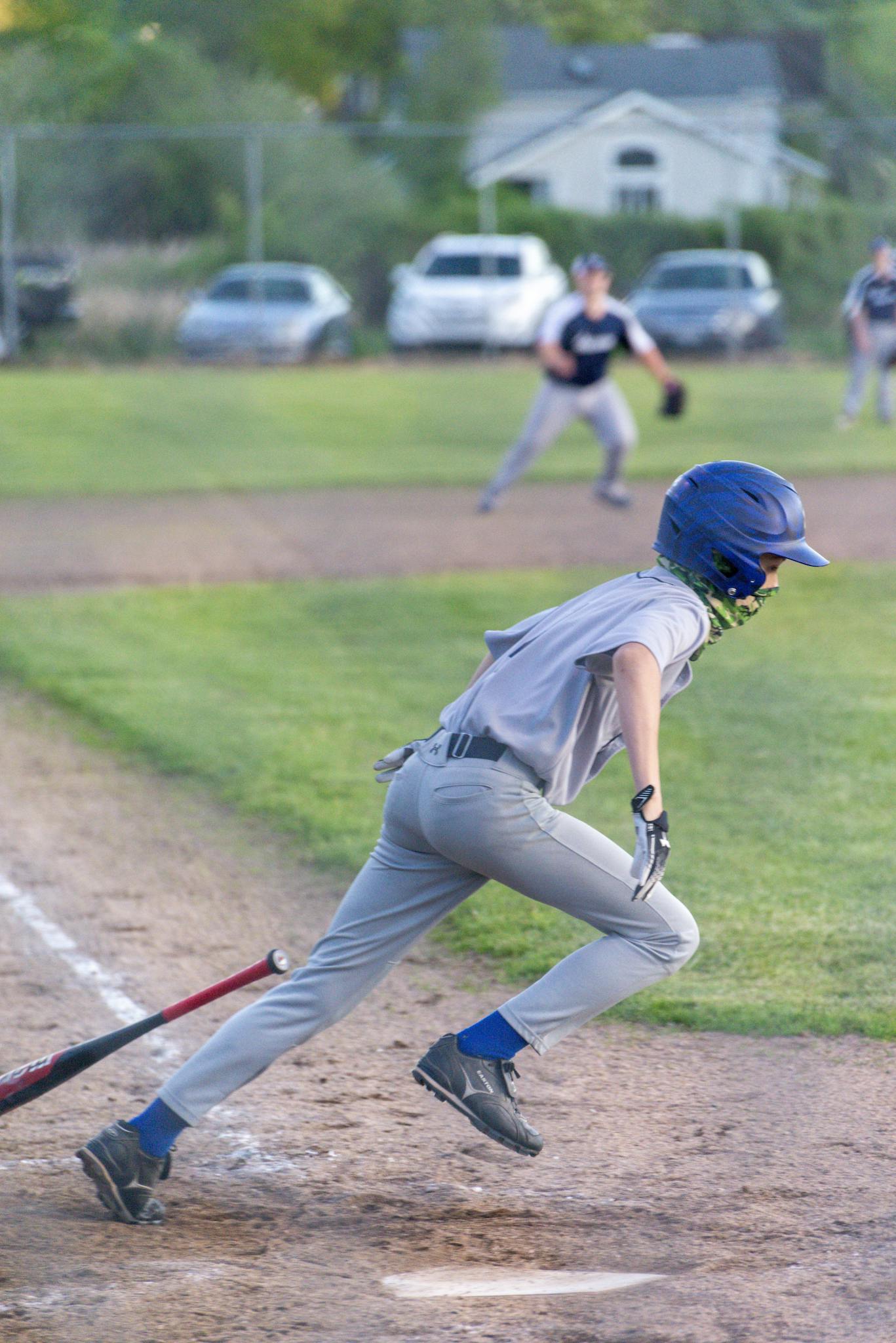 A young baseball player sprints towards first base during a game, capturing the excitement of youth sports.