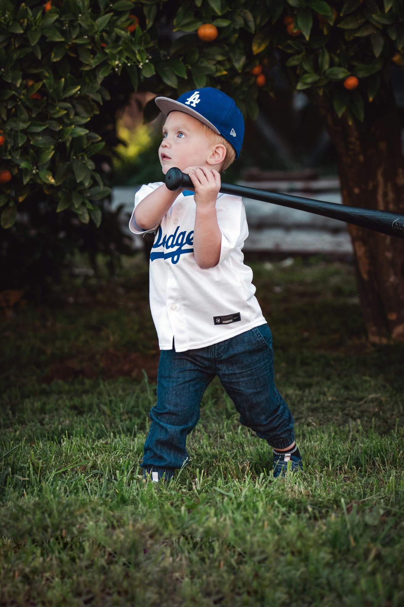 Cute young child with baseball bat in sporty outfit. Outdoor summer fun.