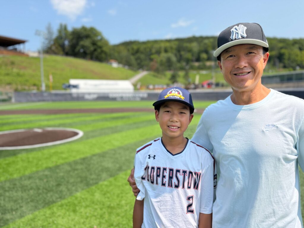 Simon Chan and son on baseball field at Cooperstown tournament