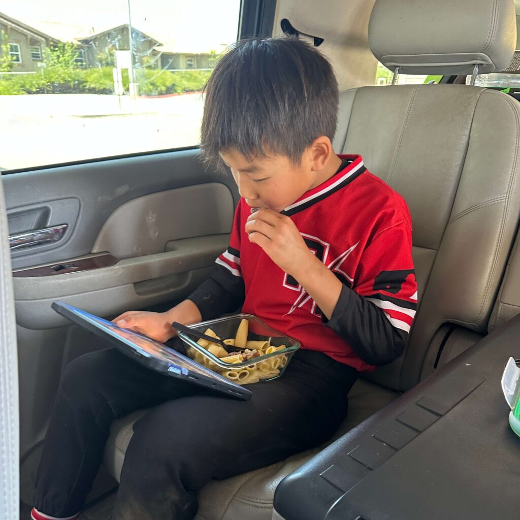 son eating pasta and steak during tournament game break and watching ipad