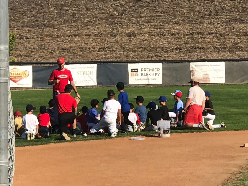 Dan doing huddle on outfield grass at a baseball camp