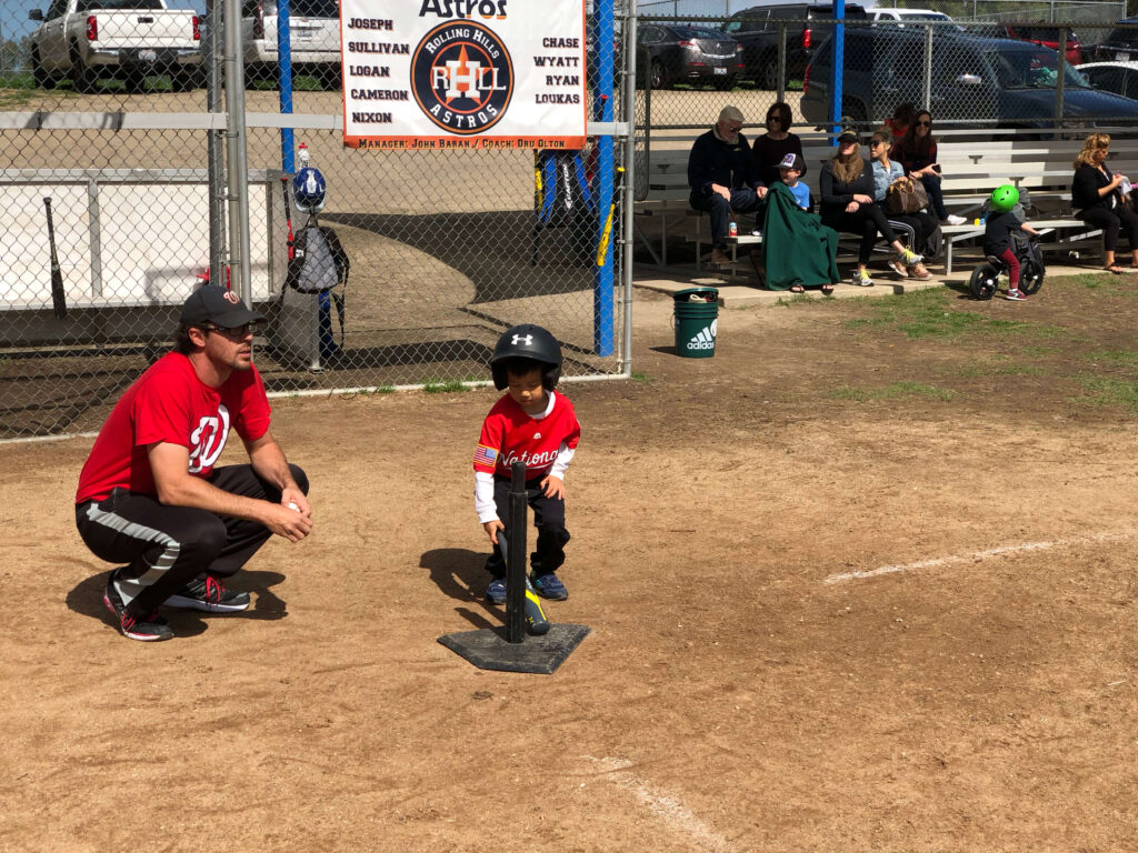 Coach Dan w young tee ball player about to hit off a baseball tee