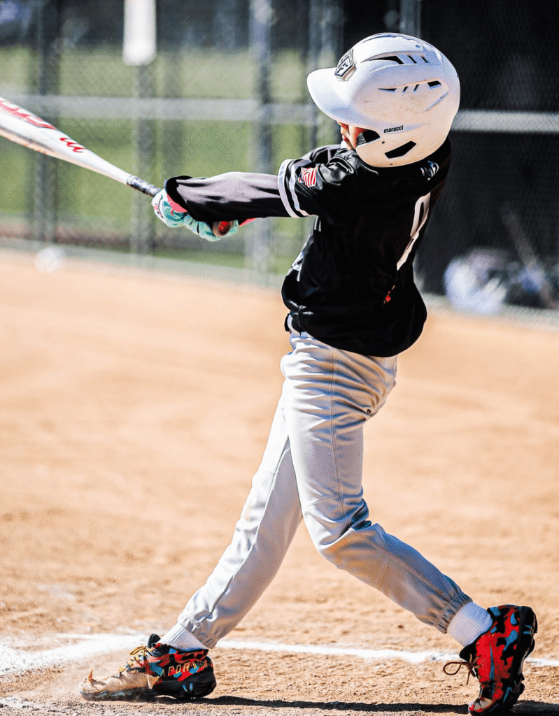 My 9 year old son swinging hard and following through during a game, demonstrating confidence at the plate.