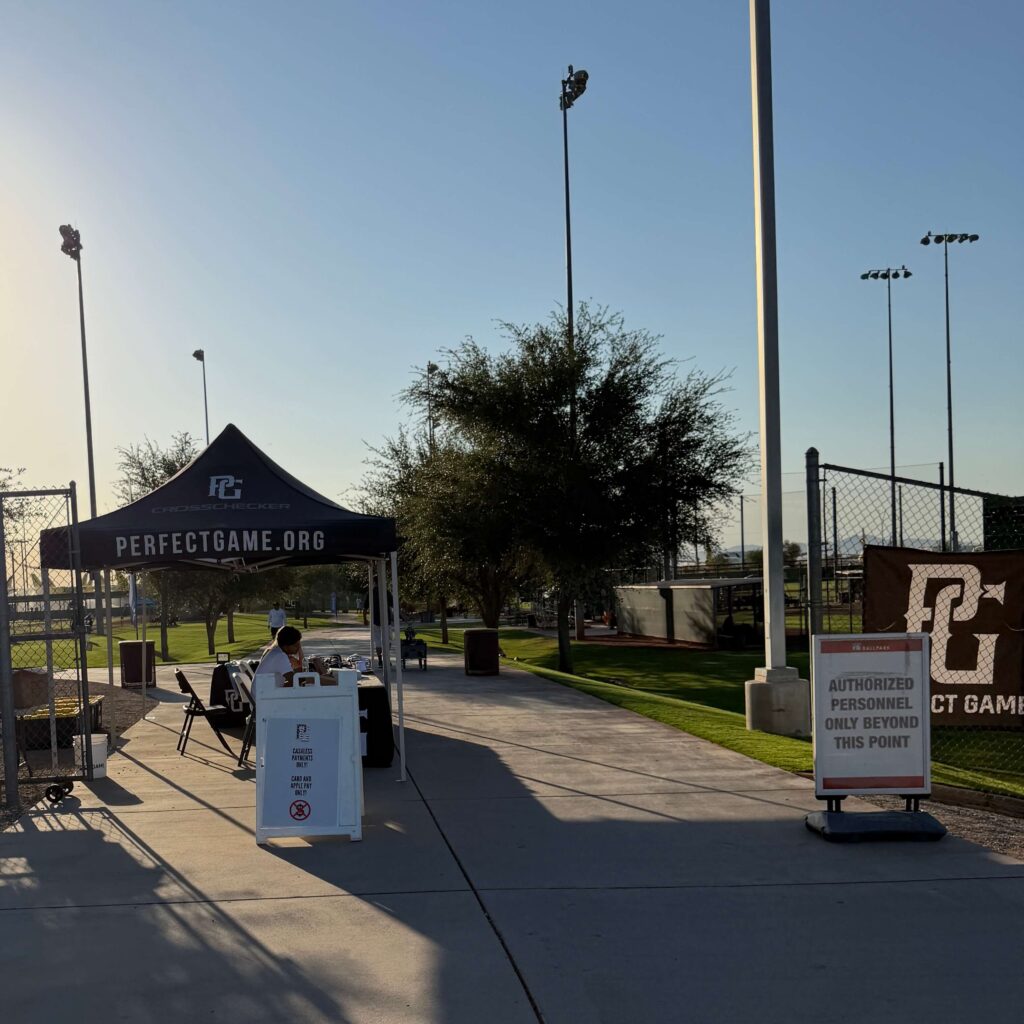 A Perfect Game tournament entrance tent and gate fee collection station at a youth baseball complex.